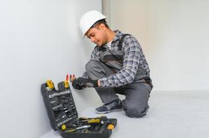 un indio electricista instala un toma de corriente en un nuevo edificio foto