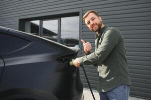 hombre participación poder cargando cable para eléctrico coche en al aire libre coche parque foto