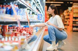 Groceries Shopping. Portrait Of Smiling Happy Woman Leaning On Trolley Cart In Supermarket photo