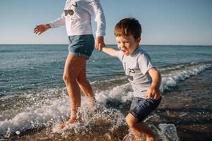 madre y hijo jugando en el playa a el puesta de sol tiempo. concepto de simpático familia. foto