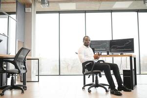 African American trader works at computer with displayed real-time stocks photo