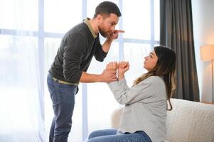 emocional hombre gesticulando y gritos a su esposa, joven Pareja teniendo pelea a hogar. Doméstico abuso concepto foto