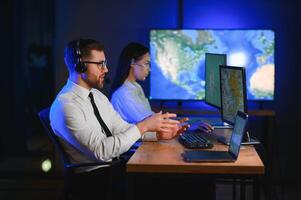 Center of dispatching maintenance. Portrait of cheerful woman and man working via headset microphone while sitting on navigation controller board photo