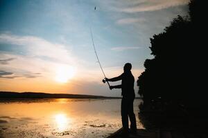 Fishing. spinning at sunset. Silhouette of a fisherman photo