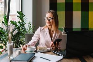 Portrait of young attractive businesswoman examining paperwork in bight light office interior sitting next to the window, business woman read some documents before meeting, filtered image. photo