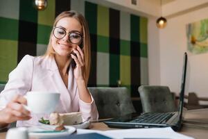 Portrait of young attractive businesswoman examining paperwork in bight light office interior sitting next to the window, business woman read some documents before meeting, filtered image photo