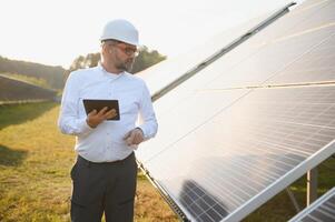 Solar power plant. Man standing near solar panels. Renewable energy photo