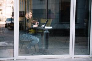 joven exitoso empresario trabajando en un ordenador portátil mientras sentado en café foto