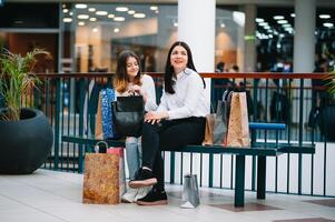 hermosa joven mamá y Adolescente hija son participación compras pantalones y sonriente mientras haciendo compras en centro comercial. familia compras foto