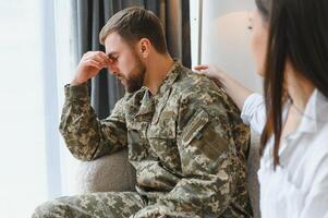 Sad male soldier on appointment with psychologist at office photo