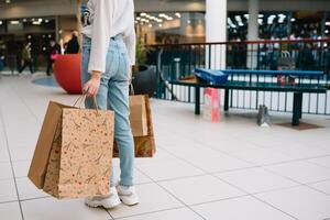 compras tiempo, de cerca de Adolescente niña piernas con compras pantalones a compras centro comercial. foto