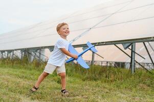 un pequeño chico es teniendo divertido cerca el solar paneles el concepto de solar energía. foto