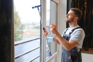 Young man washing window in office photo