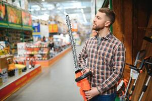 man choosing electric shears in gardening tools store photo