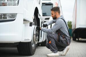 Damaged tire. Young truck driver is with his vehicle at daytime photo