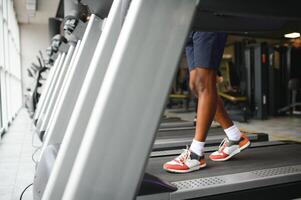 Back view of unrecognizable male legs running on treadmill in gym. photo