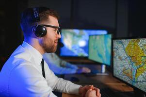 Center of dispatching maintenance. Portrait of cheerful woman and man working via headset microphone while sitting on navigation controller board photo