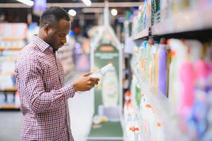 African man holding bottle of household chemicals in big store photo