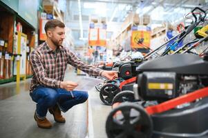 un cliente en un hardware Tienda elige un gas o eléctrico césped cortacésped foto