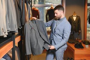 venta, compras, moda, estilo y personas concepto - elegante joven hombre en traje en centro comercial o ropa Tienda foto