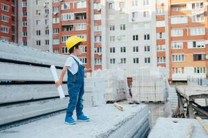 arquitecto en casco escritura alguna cosa cerca nuevo edificio. pequeño linda chico en el edificio como un arquitecto foto