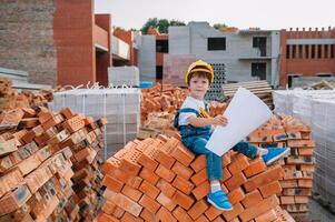 arquitecto en casco escritura alguna cosa cerca nuevo edificio. pequeño linda chico en el edificio como un arquitecto. foto