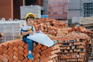 Architect in helmet writing something near new building. little cute boy on the building as an architect photo