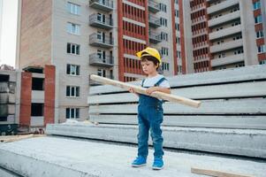 arquitecto en casco escritura alguna cosa cerca nuevo edificio. pequeño linda chico en el edificio como un arquitecto. foto