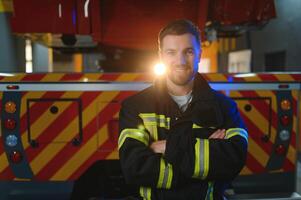 Firefighter in uniform and helmet near fire engine photo