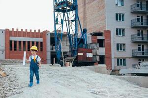 arquitecto en casco escritura alguna cosa cerca nuevo edificio. pequeño linda chico en el edificio como un arquitecto. foto