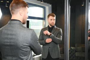 Businessman in classic vest against row of suits in shop photo