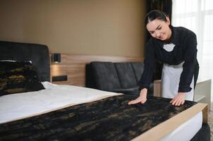 Young hotel maid making the bed photo