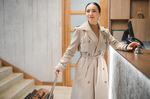 Female guests come with bags and suitcases to the hotel reception in the lobby photo