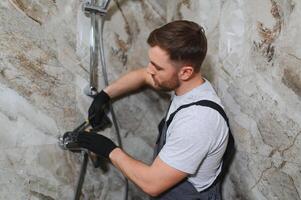 Professional handyman working in shower booth indoors photo