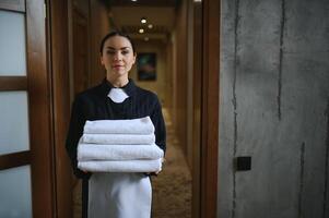 Female chambermaid holding clean white folded towels photo