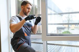 Worker installing plastic window indoors. photo