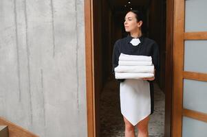 Female chambermaid holding clean white folded towels photo