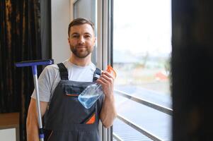 masculino profesional limpieza Servicio trabajador en mono limpia el ventanas y tienda ventanas de un Tienda con especial equipo foto