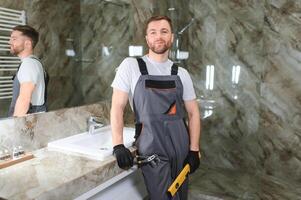 Handsome plumber working in restroom photo