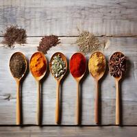 Spices and herbs in wooden spoons on a white wooden background photo