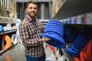 male plumber in a hardware store chooses the sewer pipes, the concept of plumbing work in the house photo