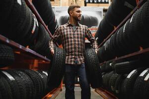 Male mechanic with car tires in automobile service center photo