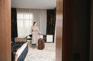 Business woman walking into hotel room with luggage photo