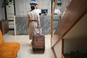 Businesswoman with luggage in modern hotel lobby photo