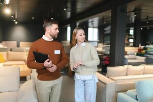 Smiling female customer looking while listening to employee discussing about sofa at store photo