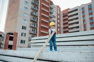 arquitecto en casco escritura alguna cosa cerca nuevo edificio. pequeño linda chico en el edificio como un arquitecto. foto