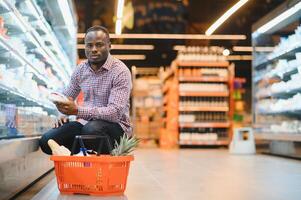 joven africano hombre comprando en tienda de comestibles sección a supermercado foto