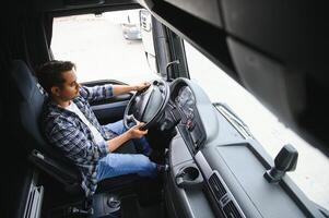 A young Indian male truck driver sits behind the wheel photo