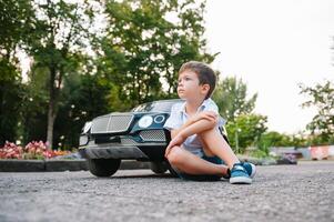 Cute boy in riding a black electric car in the park. Funny boy rides on a toy electric car. Copy space. photo