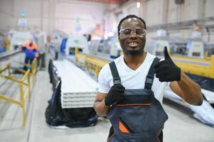 retrato de africano americano masculino ingeniero en uniforme y en pie en industrial fábrica foto